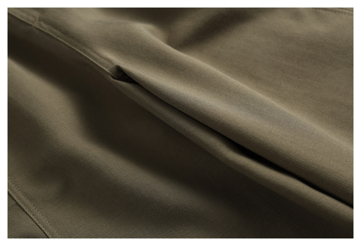 Close-up of olive-brown trouser fabric with a folded seam and visible stitching.