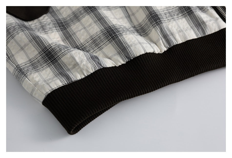 Close-up of a black ribbed hem attached to the jacket's cream and black plaid outer fabric.