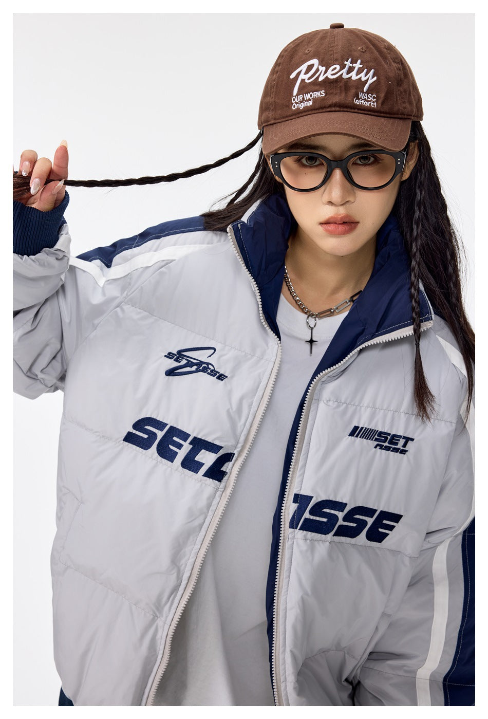 Close view of a model wearing the light gray and navy padded jacket, showing its raised collar, striped sleeves, and chest