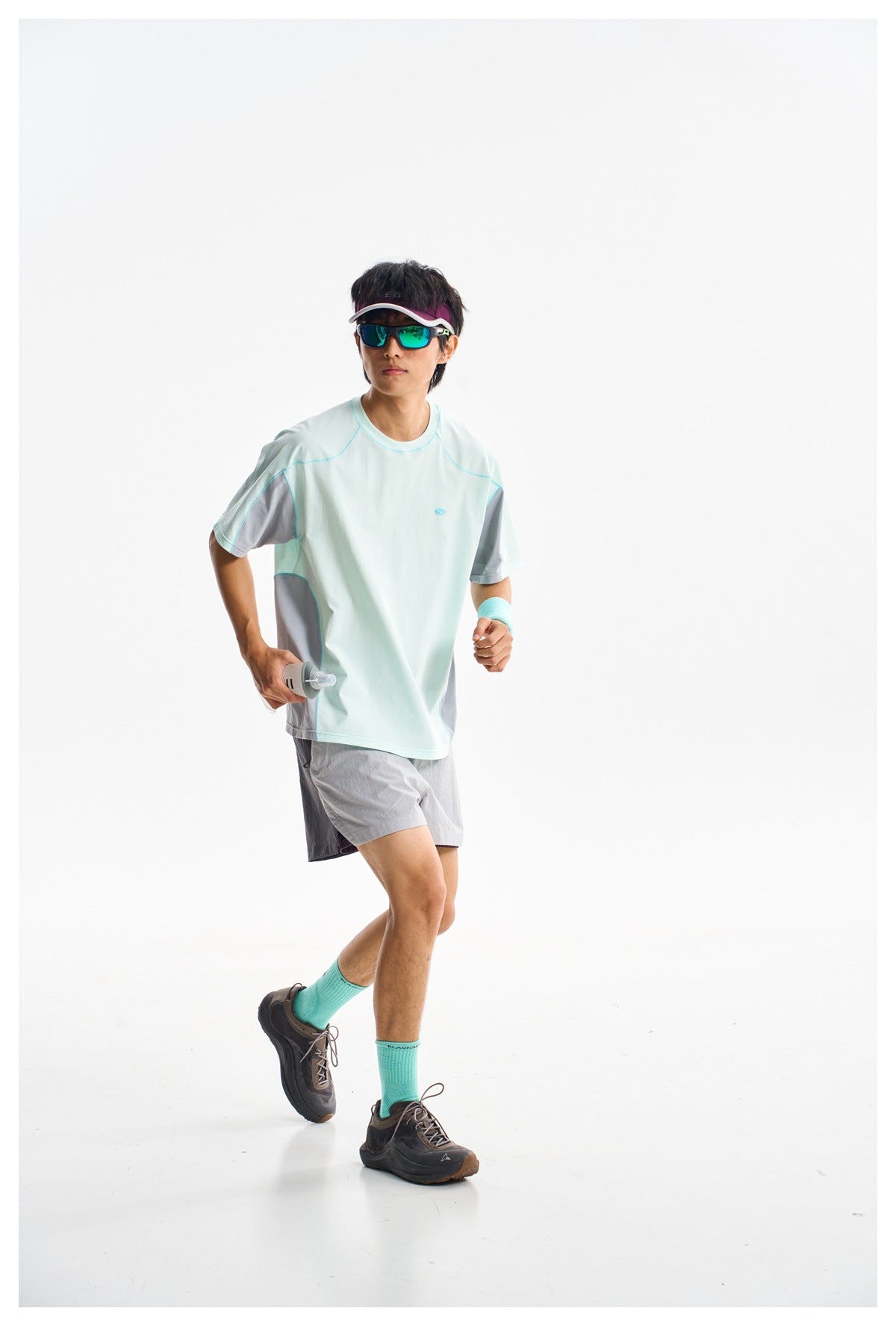Model wearing a pale mint athletic T-shirt with gray sleeve and side panels, paired with gray shorts.