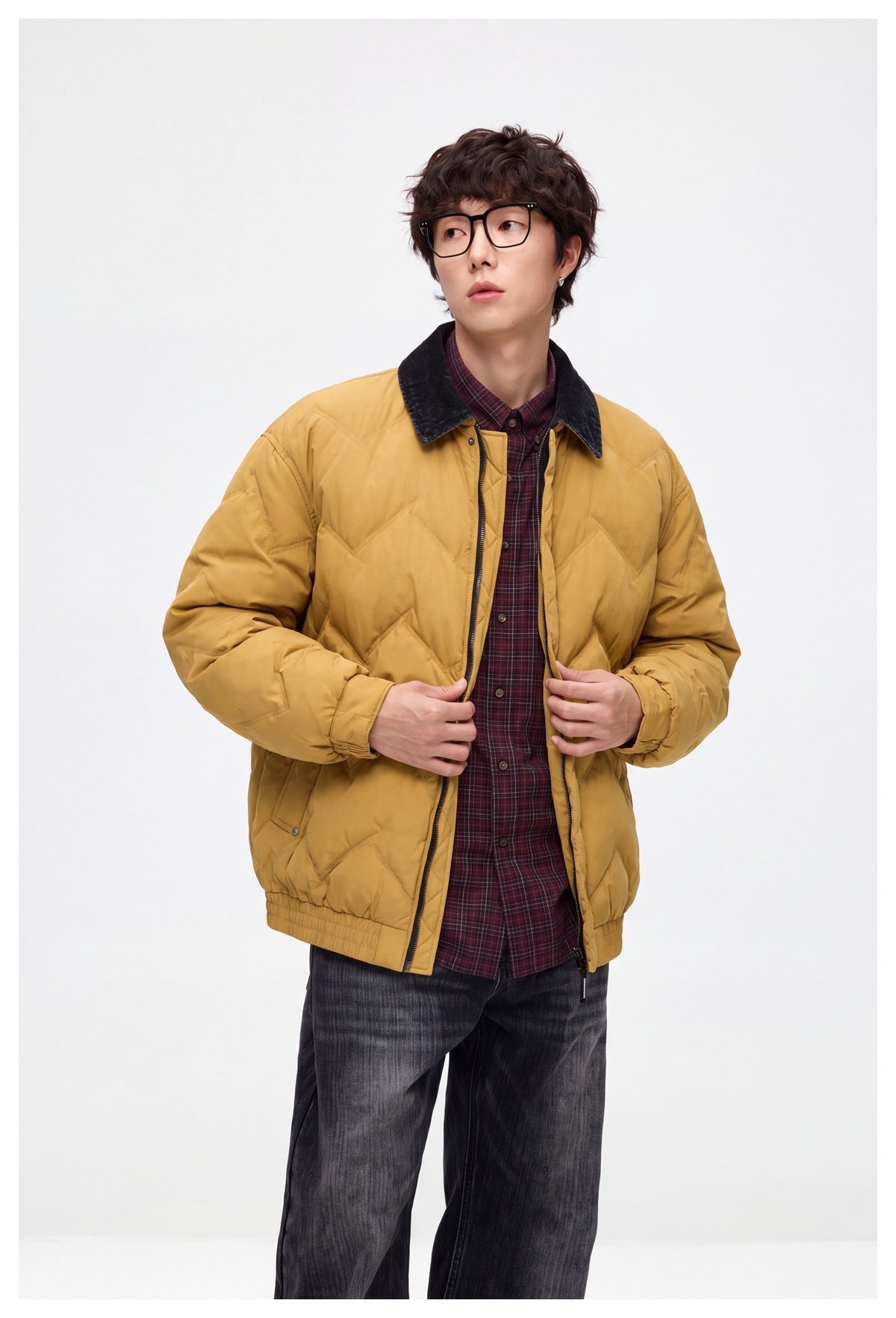 Model wearing an open mustard-yellow chevron-quilted jacket with a dark collar and snap details.