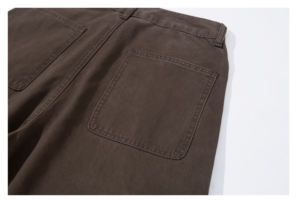 Close-up of dark brown trousers showing a stitched rectangular rear patch pocket and belt loop.