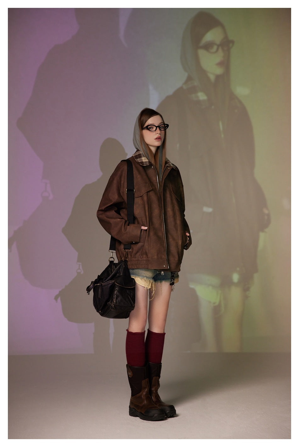 Full-length model wearing an oversized brown plaid-collar jacket, denim shorts, burgundy socks, and boots.