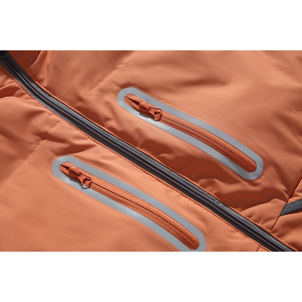 Close-up of two orange zip pockets with reflective gray borders and the vest's dark center zipper.