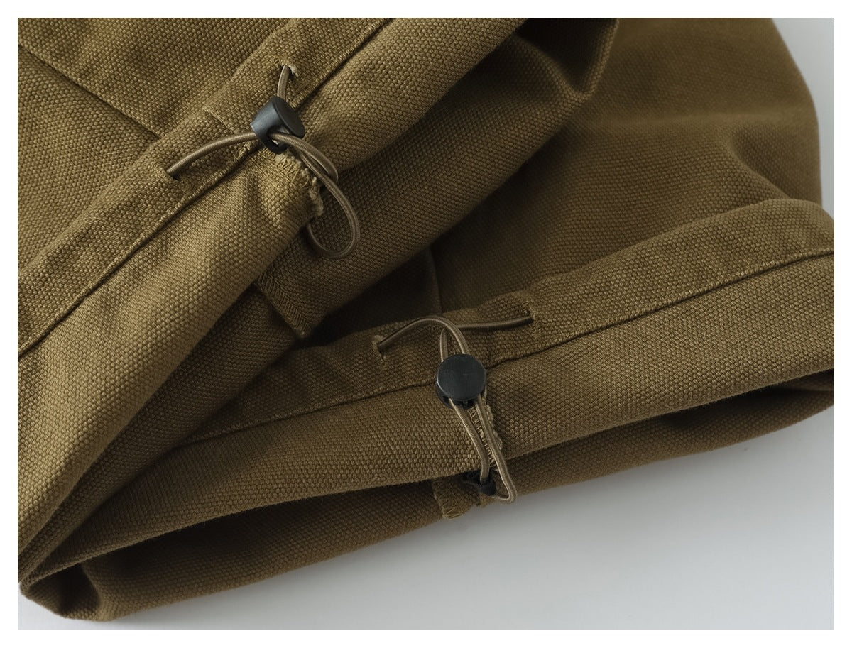Close-up of olive-brown trouser cuffs with cord loops and black adjustment toggles.