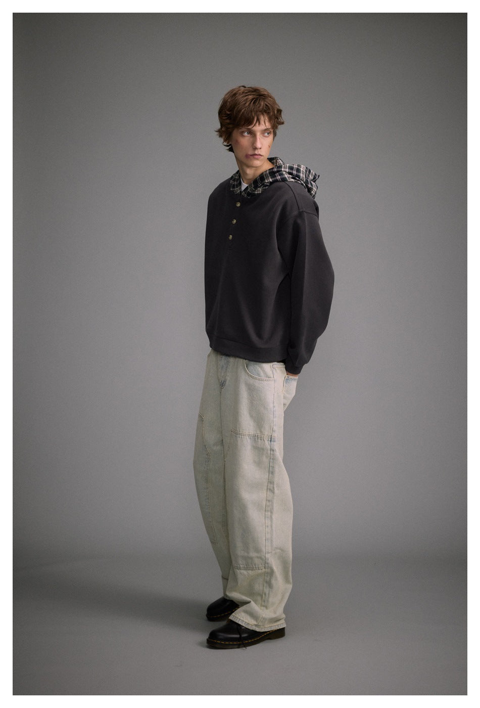 Full-length view of a model wearing a charcoal plaid-lined hooded pullover with light jeans.