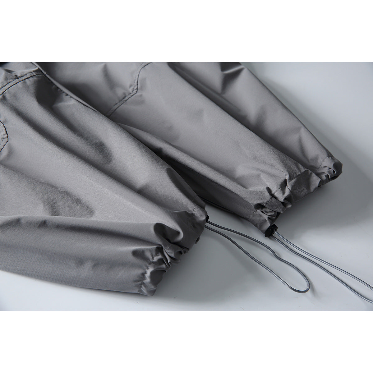 Close-up of gray cargo pants with gathered ankle cuffs and adjustable drawcords.