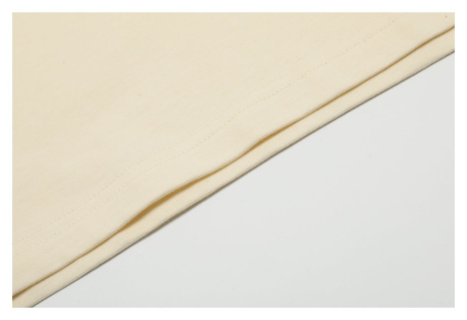 Close-up of cream fabric with a neatly stitched hem along a diagonal edge.