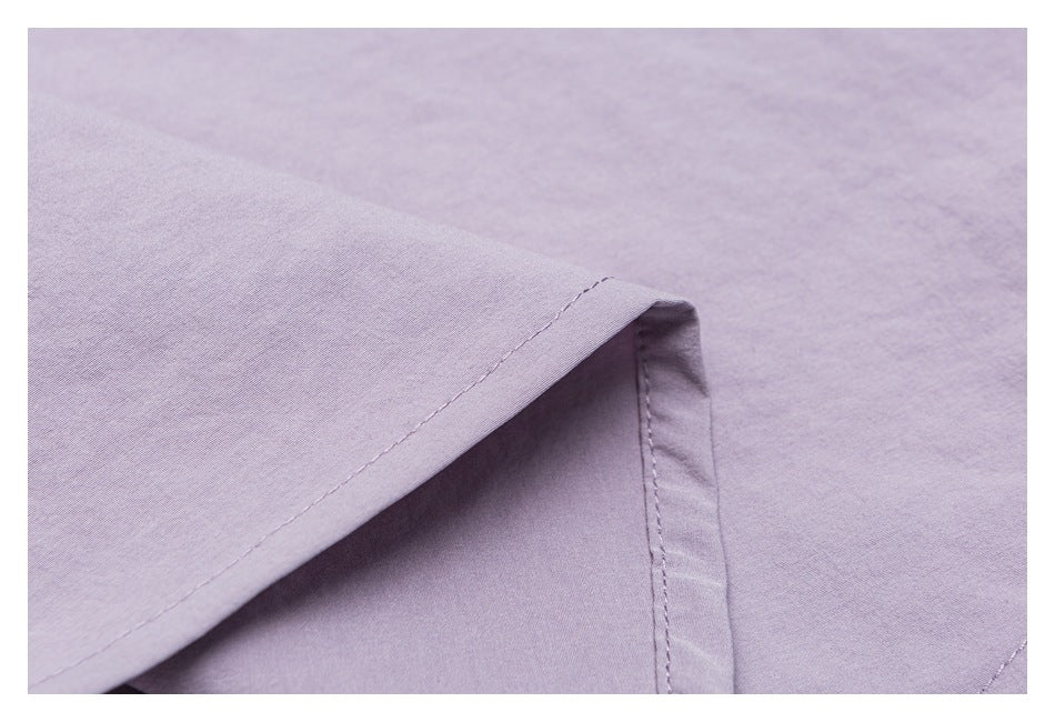 Close-up of a pale lavender garment edge with a folded, stitched hem and visible fabric texture.