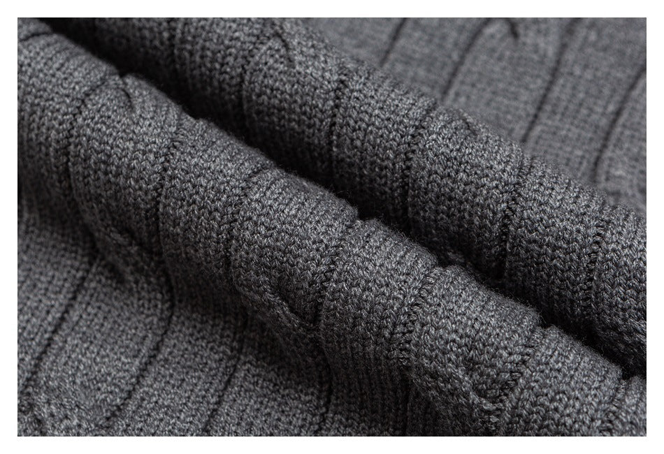 Macro view of the gray sweater's raised cable-knit pattern and textured stitches.