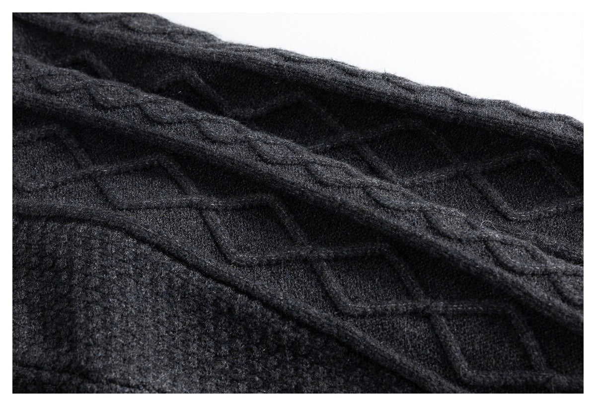 Close-up of a charcoal sweater showing raised cable-knit pattern and textured knit stitches.