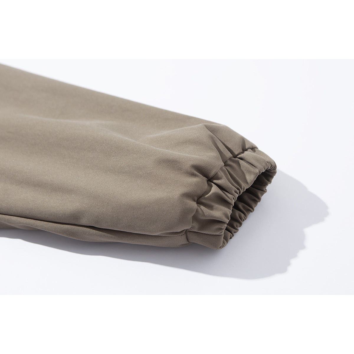 Close-up of a taupe jacket sleeve ending in a gathered elastic cuff.