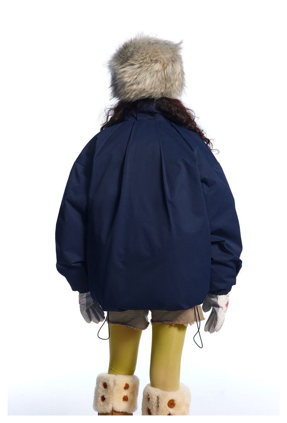 Rear view of a model wearing a dark navy oversized jacket with gathered cuffs and adjustable drawcords at the hem.