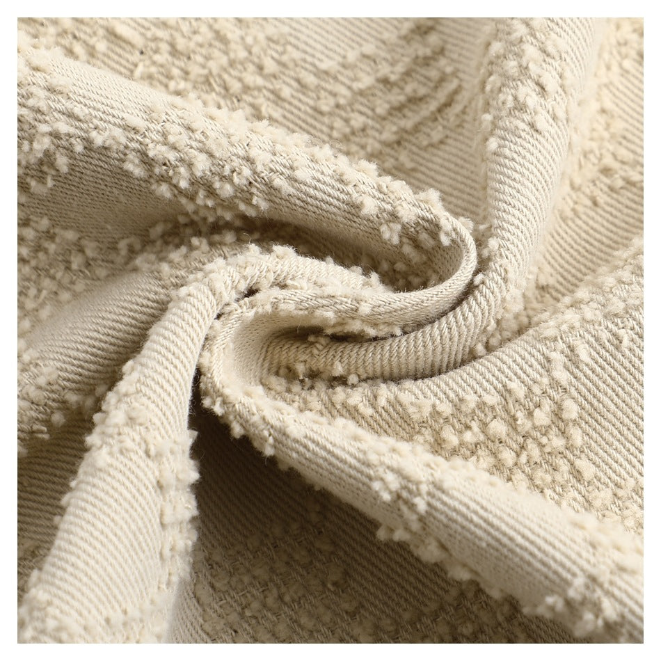 Macro view of the beige trousers' raised check texture, woven surface and folded edge.