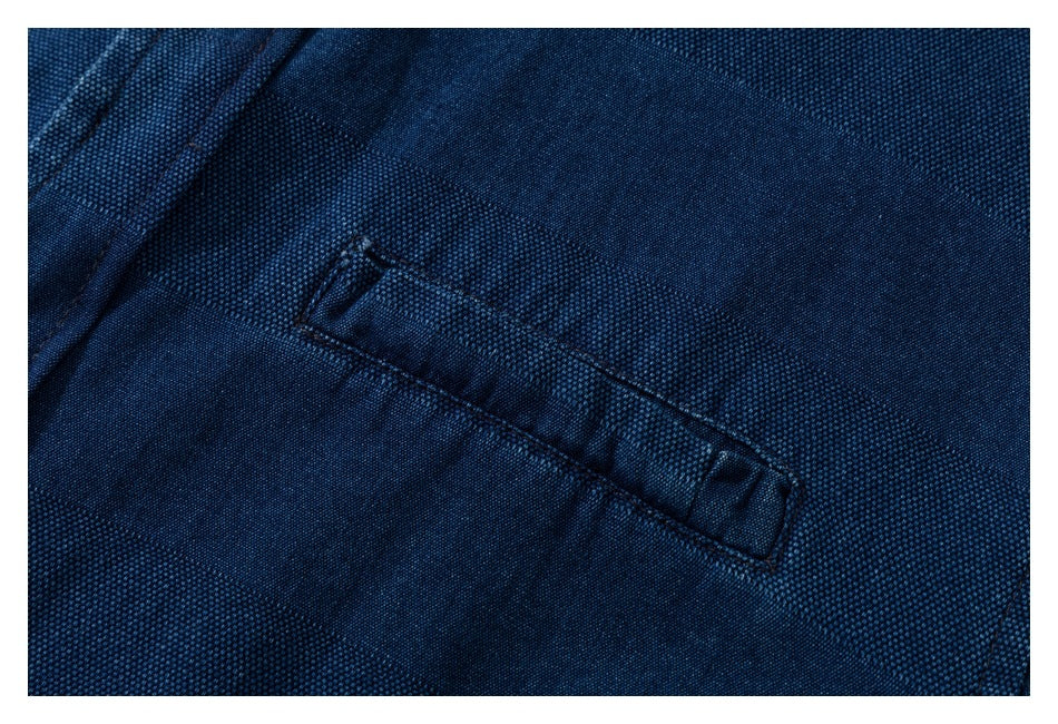 Close-up of a welt pocket on navy shirt fabric with a subtle stripe texture.
