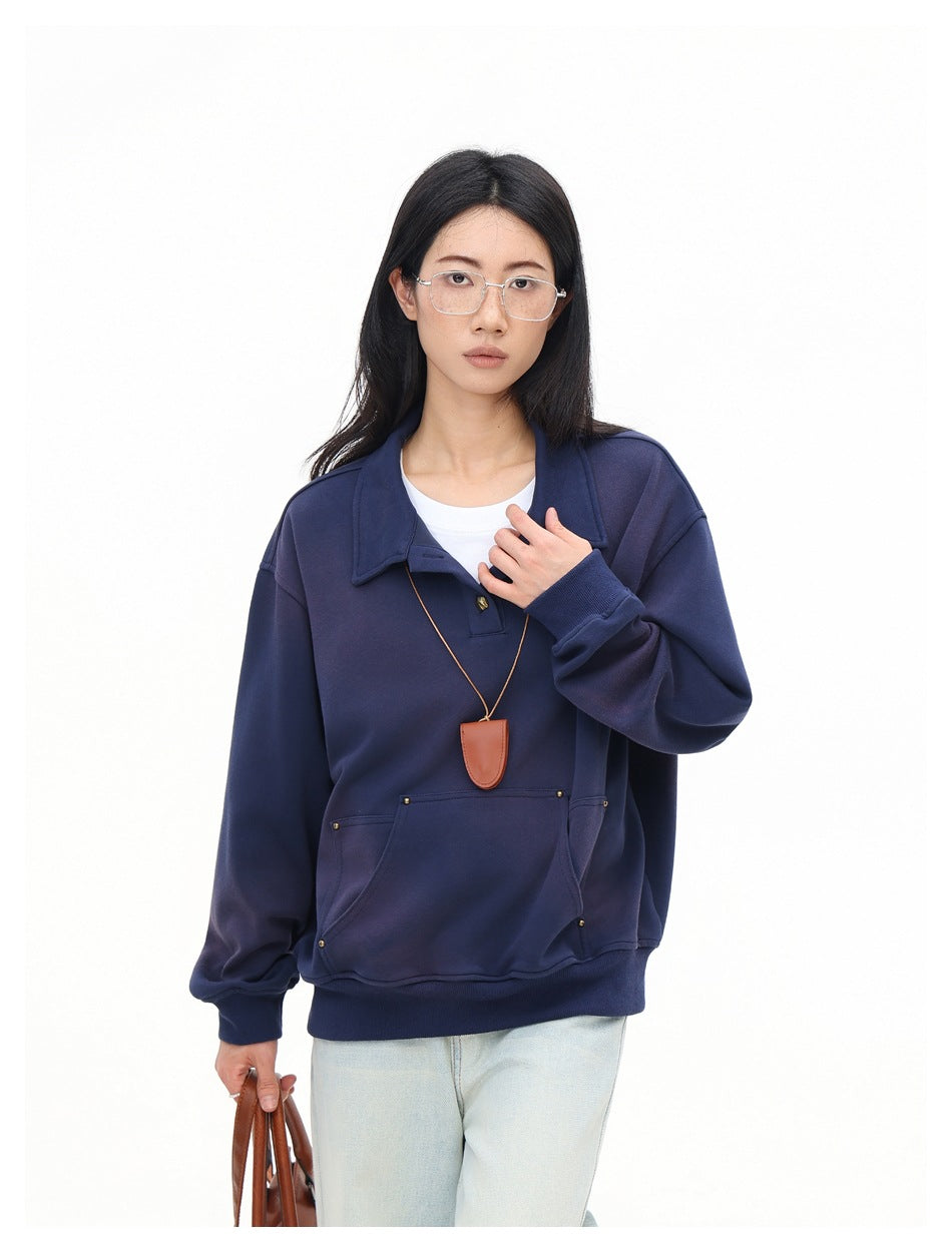 Close view of model in navy polo-collar sweatshirt with kangaroo pocket, ribbed cuffs and a brown pendant necklace