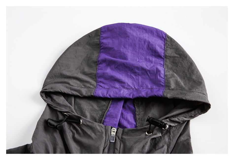 Close-up of a charcoal hood with a purple center panel, drawcords, and zipper.