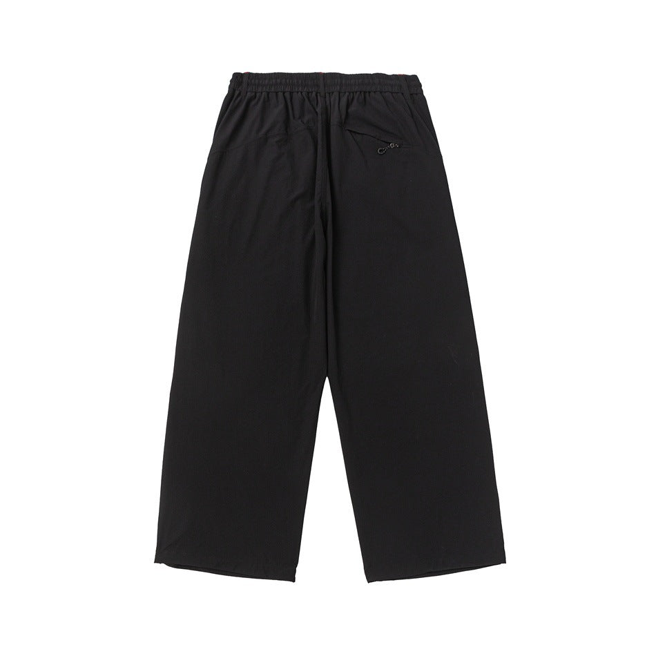 Back view of black wide-leg trousers with an elastic waistband and a small zip pocket.