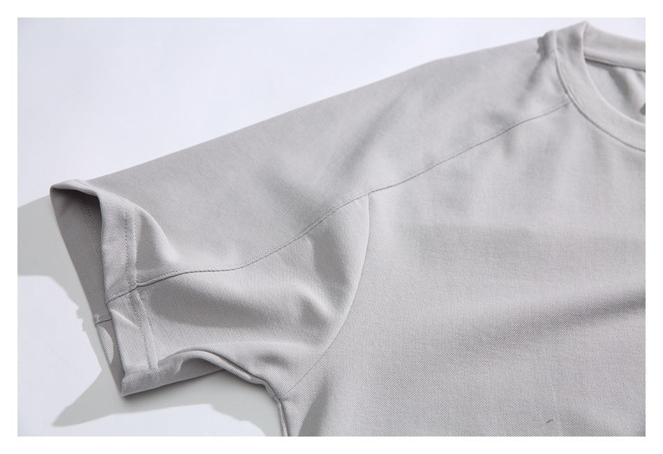 Close-up of the light gray T-shirt's short sleeve and raglan-style shoulder seam.
