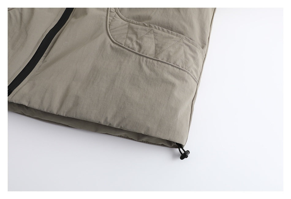 Close-up of the taupe jacket's lower pocket, hem, and adjustable drawcord toggle.