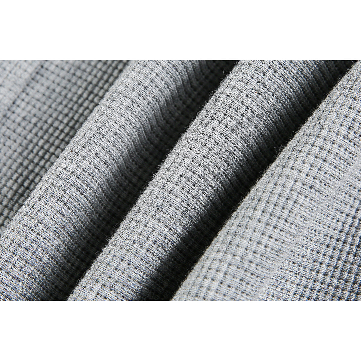 Macro view of the jacket's gray textured knit fabric, shown in folds.