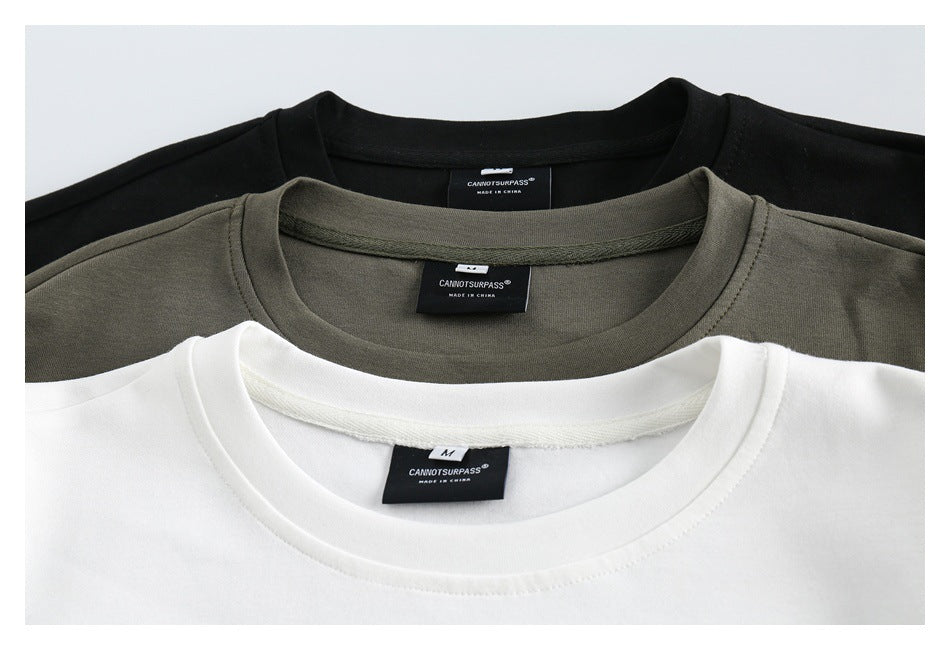 Close-up of black, olive-gray, and white crewneck sweatshirts showing their collars and sewn-in neck labels.