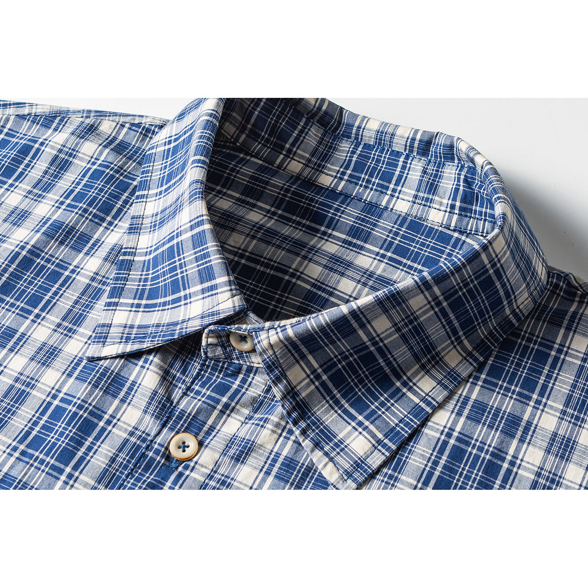 Close-up of a blue and white plaid shirt collar and button placket.