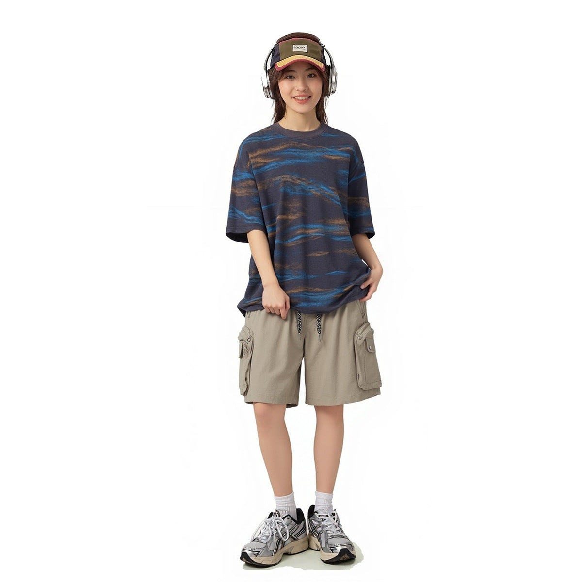 Model wearing an oversized navy T-shirt with blue and brown wavy stripes and beige cargo shorts.