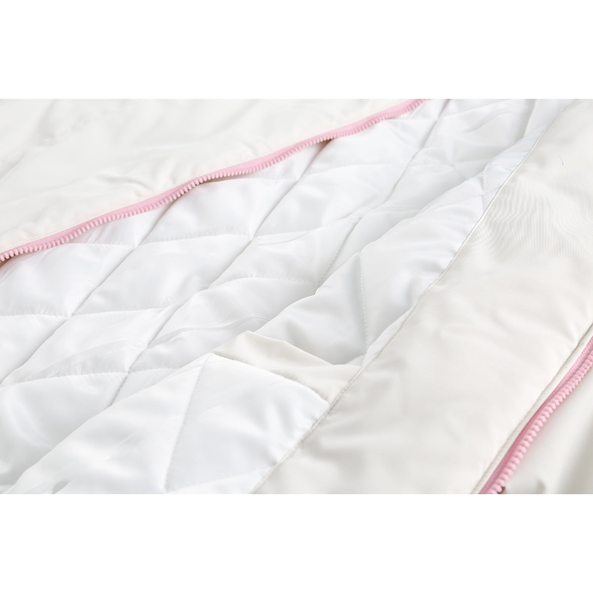 Close-up of a white jacket's quilted lining and pink zipper.