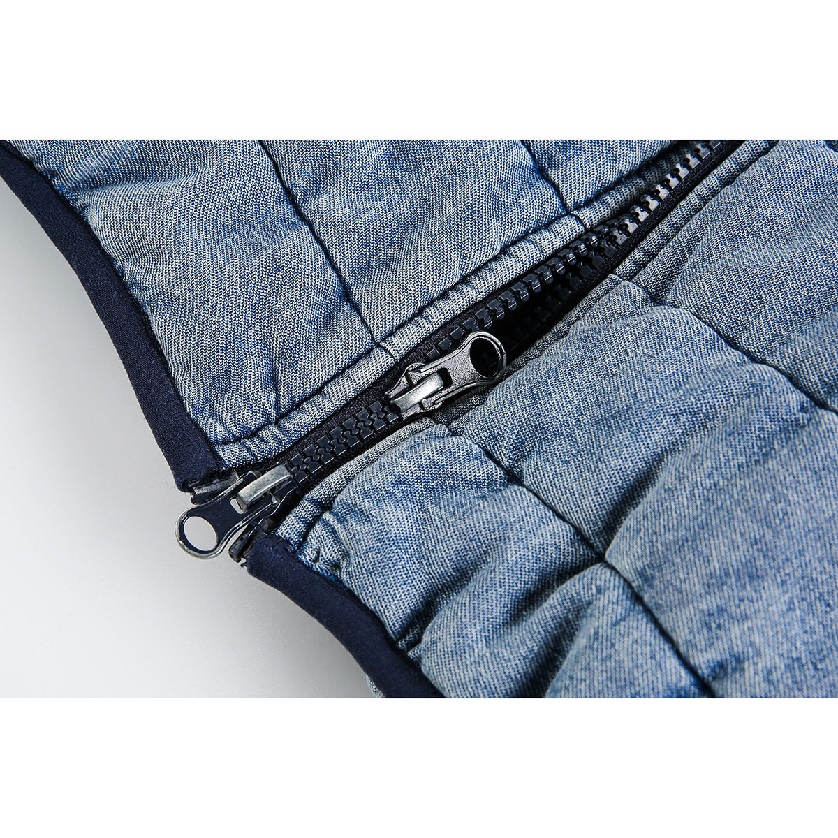 Close-up of a black two-way zipper on light blue quilted jacket fabric.