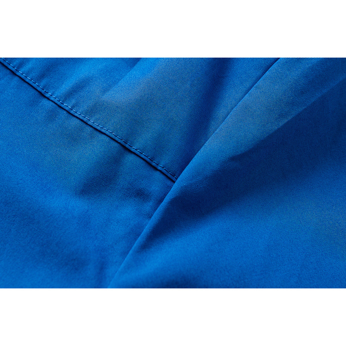 Macro view of bright blue shirt fabric with a stitched seam and folded section.