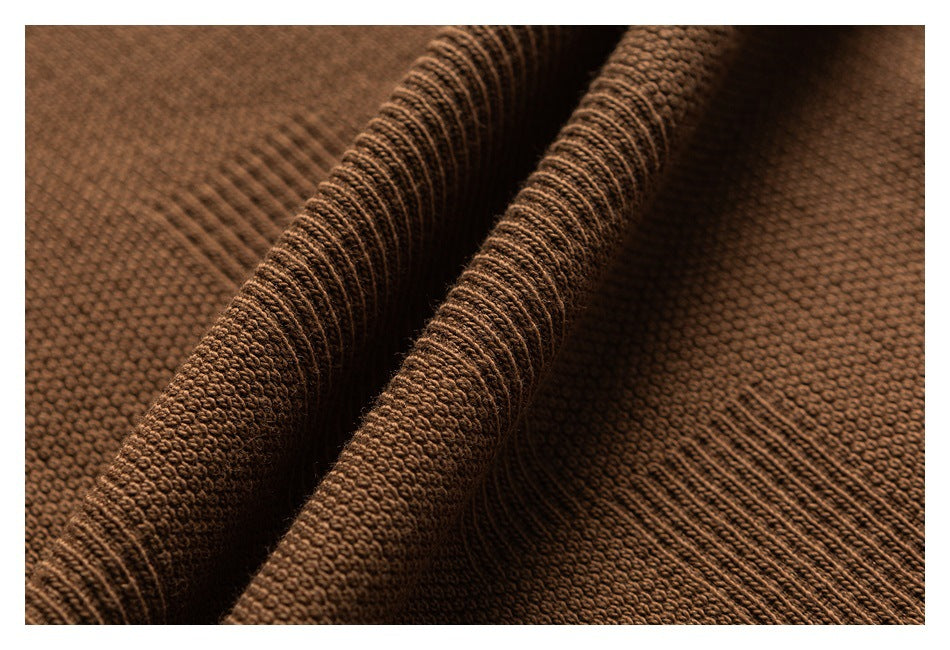 Macro view of brown knit fabric, highlighting its textured stitches and ribbed seam.