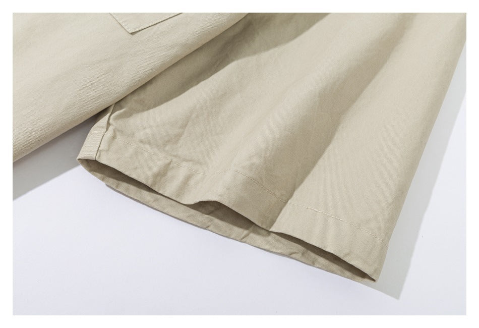 Close-up of a beige garment hem and folded fabric edge with visible stitching.