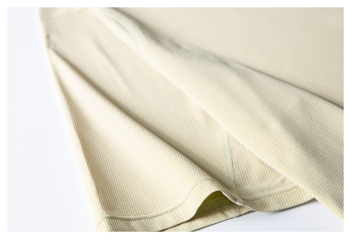 Close-up of pale yellow patterned fabric showing a curved stitched seam and hem edge.