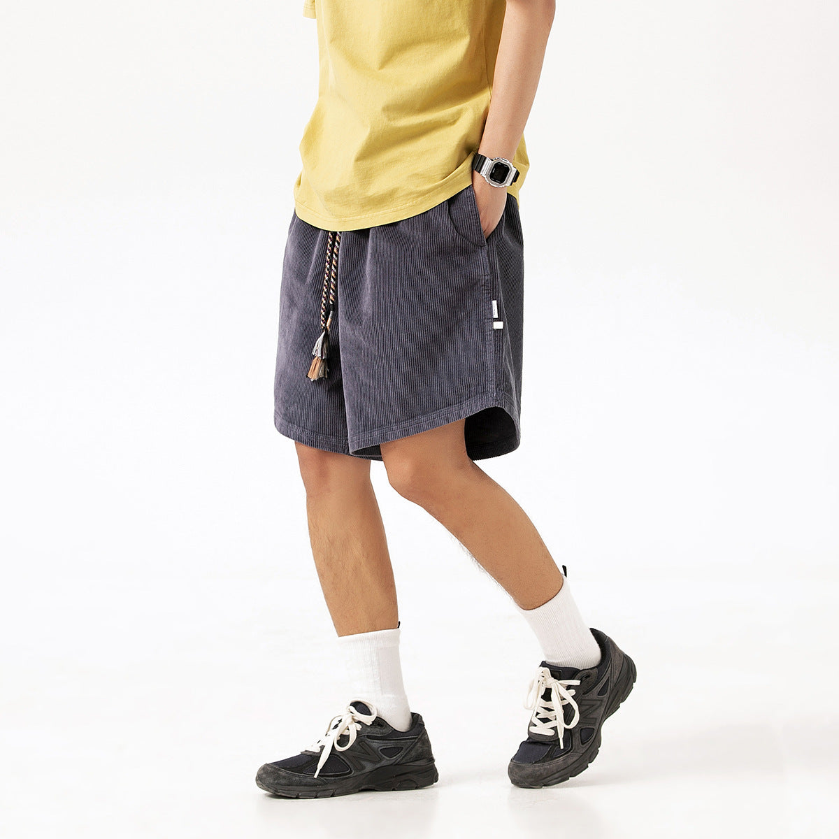 Model wearing charcoal gray knee-length shorts with a braided tassel drawstring and side pockets.