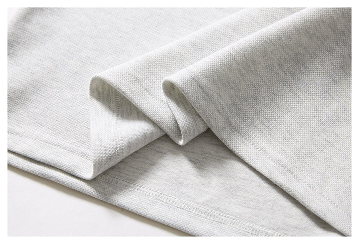 Close-up of the light gray knit shirt's folded hem and overlocked seam.