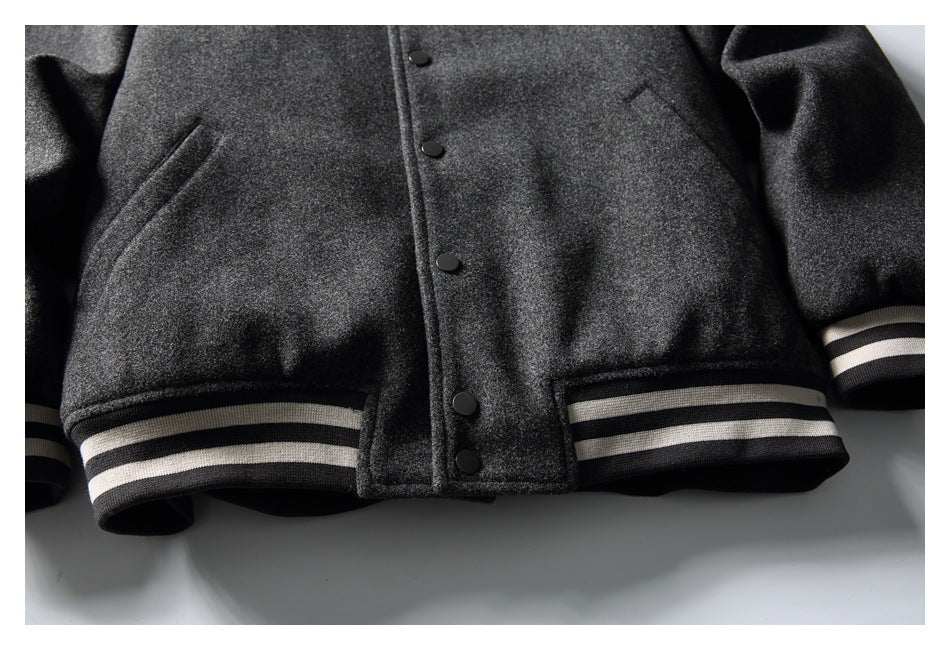 Close-up of a charcoal jacket front with black snap buttons, a slanted pocket, and black-and-cream striped ribbed hem and
