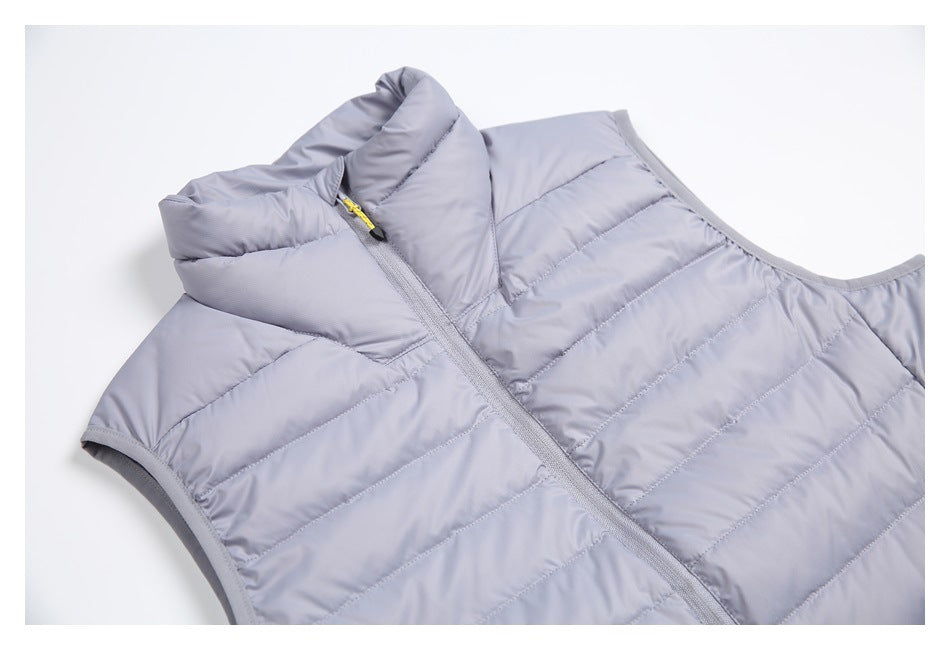 Close-up of the light gray vest's padded collar, front zipper, quilted panels, and bound armhole.