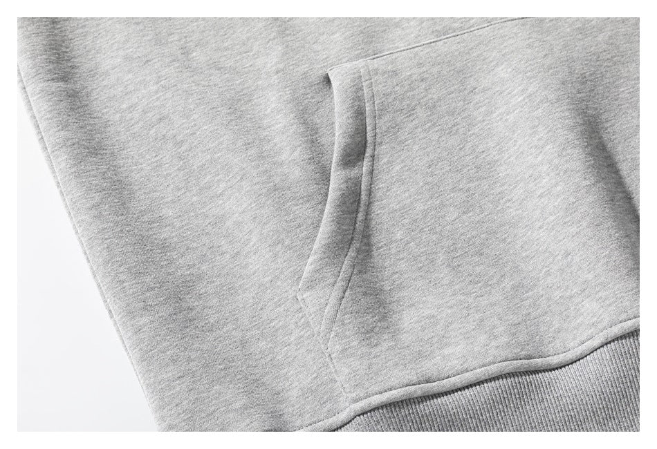 Close-up of a light gray sweatshirt's kangaroo pocket and ribbed hem.
