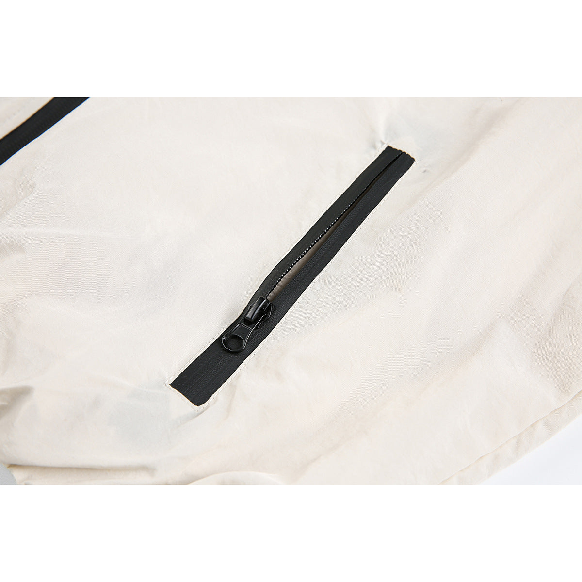 Close-up of a black zipper on cream fabric, with a second zipper partly visible at the upper left.