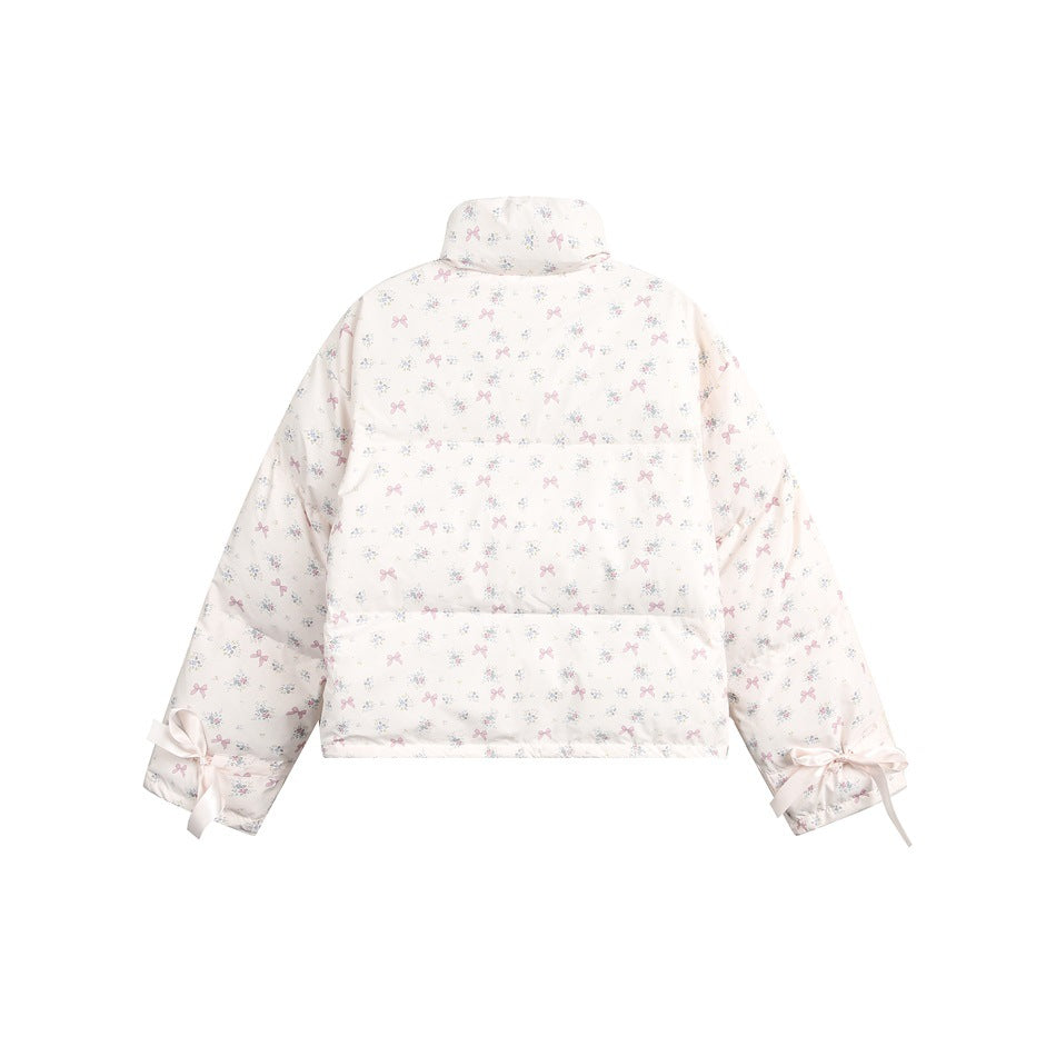 Back of a white jacket with a pastel bow-and-floral print and ribbon-tied cuffs, shown flat.