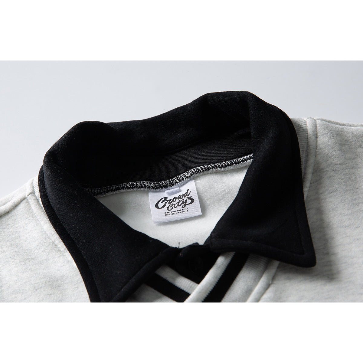 Close-up of a light gray sweatshirt with a wide black collar and a small sewn neck label.