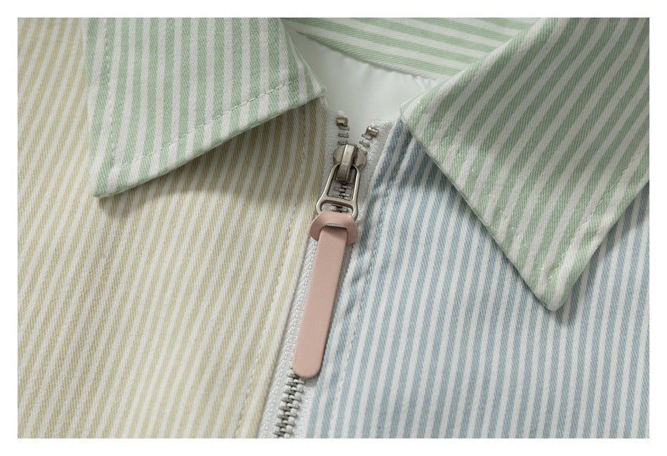 Close-up of the jacket's metal zipper with a pink pull between pastel striped panels.