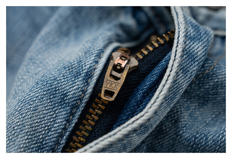 Close-up of the metal zipper and fly on blue denim jeans; the zipper pull is marked YKK.