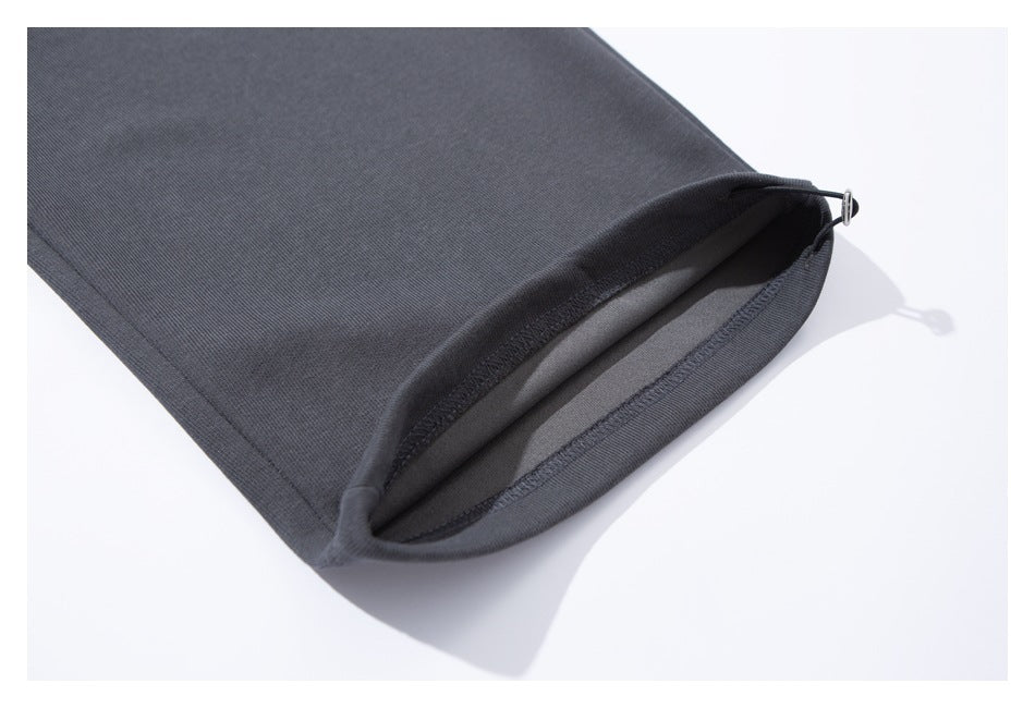 Close-up of a charcoal pants leg hem with a small adjustment cord and metal toggle.