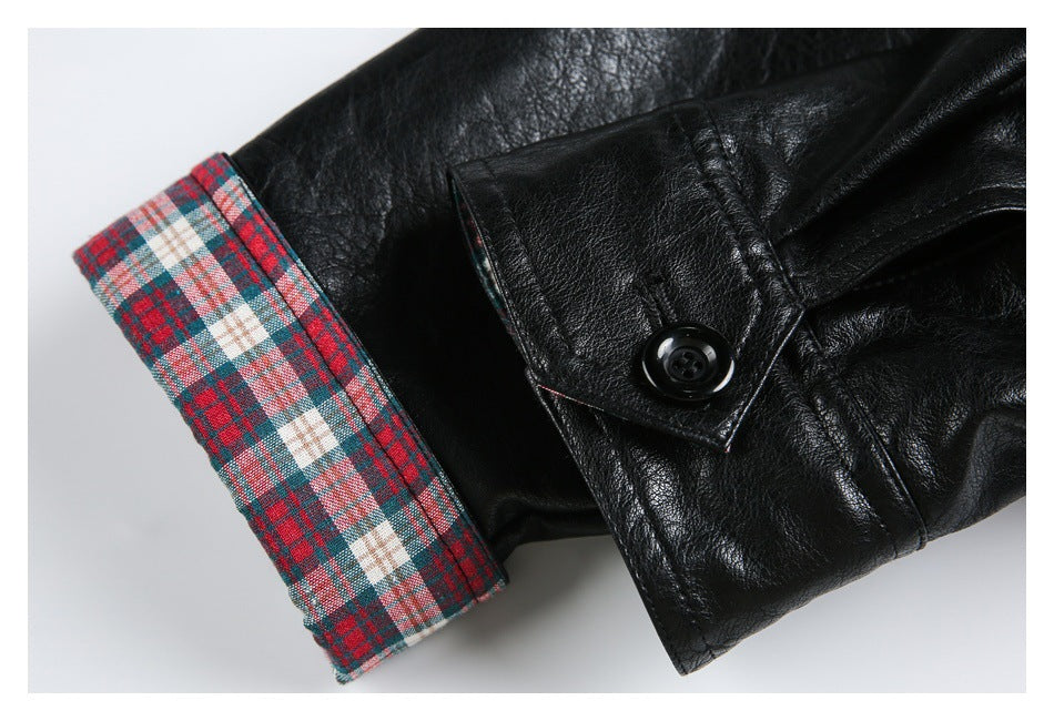 Close-up of a black jacket sleeve with a red, teal, and cream plaid cuff and a black button tab.