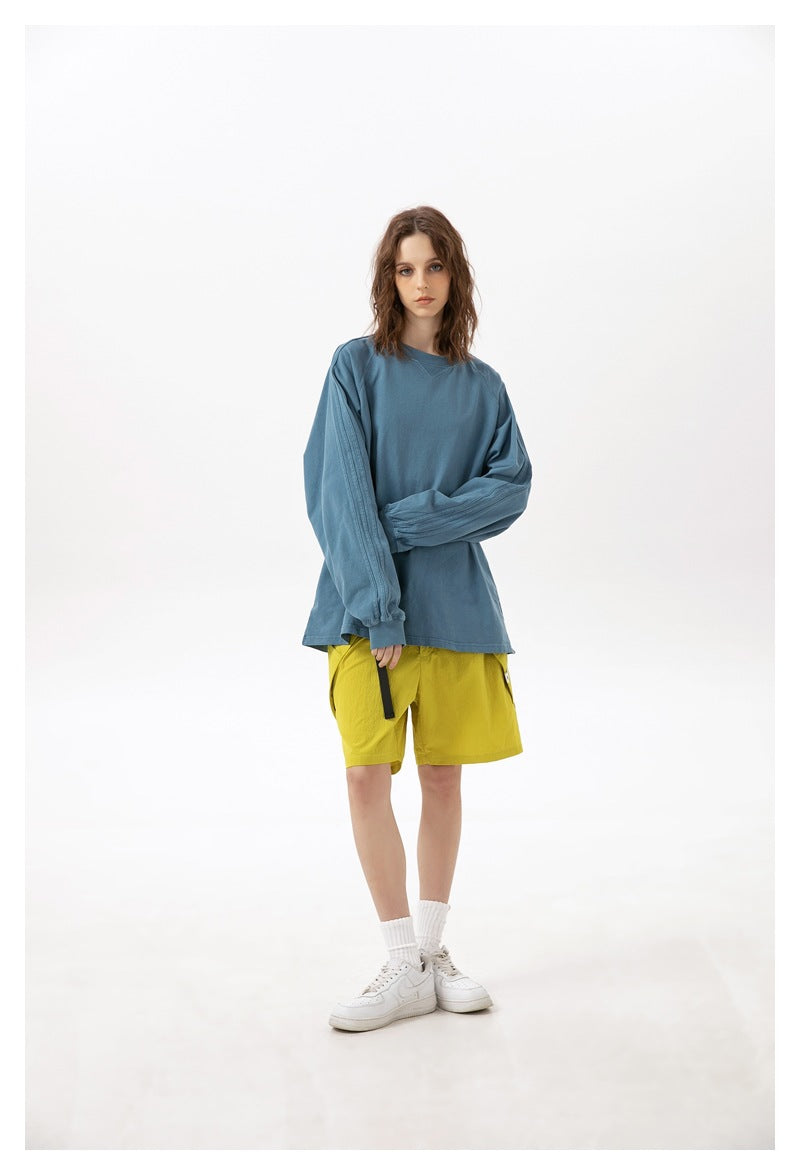 Model wearing a blue long-sleeve shirt and bright yellow shorts with white sneakers, front view.