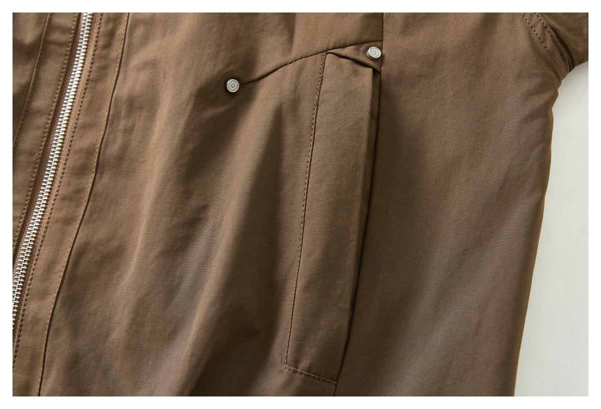 Close-up of a brown jacket's front panel with a vertical pocket flap, snap buttons, and zipper edge.