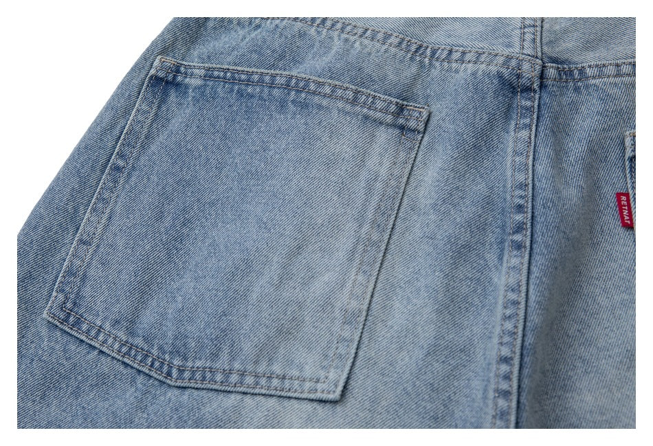 Close-up of a light blue denim back pocket with contrast stitching and a red tab at the edge.