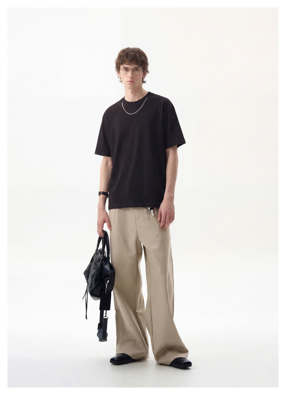 Full-length front view of a model in a plain black crew-neck T-shirt and beige wide-leg trousers.